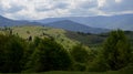 The alpine ridges of the Carpathian Mountains are surrounded by centuries-old forests on the background of the blue sky with white Royalty Free Stock Photo