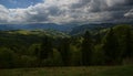 The alpine ridges of the Carpathian Mountains are surrounded by centuries-old forests on the background of the blue sky with white Royalty Free Stock Photo