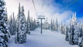 Alpine ski lift amidst snow covered trees and blue sky Royalty Free Stock Photo