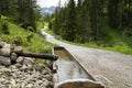 Alpine stream running into old wooden water trough in Austrian Alps in Tannheim valley or Tannheimer Tal, Tirol, Austria Royalty Free Stock Photo