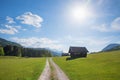 Alpine walkway near Gerold, spring landscape with huts and bright sun, blue sky with clouds