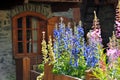 Alpine window with violet and pink flowers Royalty Free Stock Photo