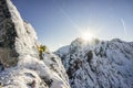 An alpinist climbing a steep ice, snow and rock face in alpine mountain landscape of High Tatras