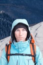 Alpinist man with a backpack on a background of mountain scenery. Looking at the camera.