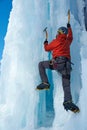 Alpinist man with ice tools axe climbing a large wall of ice. Outdoor Sports Portrait