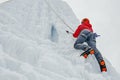 Alpinist woman with ice tools axe in orange helmet climbing a large wall of ice. Outdoor Sports Portrait. Royalty Free Stock Photo