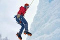 Alpinist woman with ice tools axe in orange helmet climbing a large wall of ice. Outdoor Sports Portrait Royalty Free Stock Photo