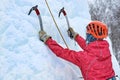 Alpinist woman with ice tools axe in orange helmet climbing a large wall of ice. Outdoor Sports Portrait Royalty Free Stock Photo