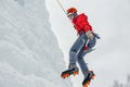 Alpinist woman with ice tools axe in orange helmet climbing a large wall of ice. Outdoor Sports Portrait Royalty Free Stock Photo