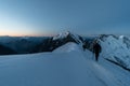 Alpinists on snowy ridge early before sunrise, Aiguille de Bionnassay, Mont Blanc massif, France Royalty Free Stock Photo