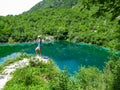 Alps Adria - Rear view of woman sitting at turquoise colored Lake Cornino near Udine, Friuli-Venezia Giulia, Italy, Europe