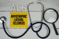 ALS Amyotrophic Lateral Sclerosis text with Stethoscope on wooden background Royalty Free Stock Photo