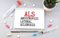 ALS Amyotrophic Lateral Sclerosis written in notebook on white table Royalty Free Stock Photo