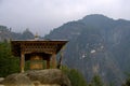 Large Tibetan `Mani` Prayer Wheel along trail to Paro Taktsang Tiger`s Nest Monastery, with the temple complex in the background Royalty Free Stock Photo