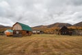 Altai autumn farm. Wooden house on hill, wooden cabin. Haystacks in the yard, remote remote mountain village Royalty Free Stock Photo