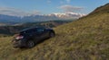 Crossover Nissan X-TRAIL on the hillside in Kurai steppe against the backdrop of the North Chuy ridge at dawn.