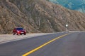 Sedan car Hyundai Solaris in red color stand on parking near asphalt road highway in Altai mountains. Travelling by car