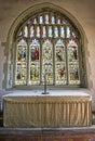 Altar and beautiful stained glass window of ancient St Mary`s Church Pevensey