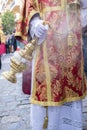 Altar boy or acolyte in the holy week procession shaking a censer to produce smoke and fragrance of incense