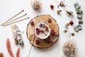 Altar with candle decorated with stones and dried flowers on a piece of wood. Bundle of sage and matches