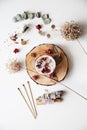 Altar with candle decorated with stones and dried flowers on a piece of wood. Bundle of sage and matches