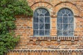 Old clinker house facade with two arched windows and vegetation Royalty Free Stock Photo