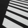 Alternating light and shadow create striking linear patterns on a surface. The shadows