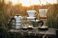 Alternative coffee brewing outdoors in travel. Steel kettle, hot coffee in cup, coffee dripper, geyser maker, glass flask with