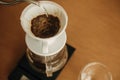 Alternative coffee brewing v60 closeup. Barista making filter coffee on brown background. Pouring hot water from steel kettle in