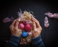 Alternative Easter composition in dark style with eggs, feather and hands of senior woman over black background Royalty Free Stock Photo