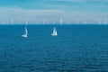 Alternative energy - row of offshore wind turbines and yachts at sea, green energy windmill generators at sea Royalty Free Stock Photo