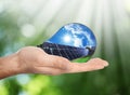 Alternative energy source. Man holding light bulb with solar panels Royalty Free Stock Photo