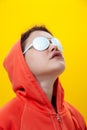 Close up fashion portrait young beautiful woman in hoodie and white glasses. Alternative funky girl on a bright yellow Royalty Free Stock Photo