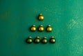 Alternative green and yellow christmas balls make tree on jade green background with gold colored glitter. Christmas Holidays and