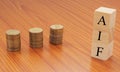 Alternative investment Funds or AIF on wooden block letters with Stack of currency coins.