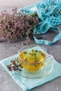 Alternative medicine. A cup of tea with oregano on the table and a dry bunch of herbs nearby