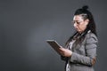 alternative woman dressed in jacket suit looks at her tablet in studio shot