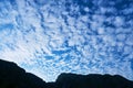 Altocumulus floccus clouds, blue morning sky, and a mountain ridge silhouette. Location: Trascau mountains part of Carpathians. Royalty Free Stock Photo