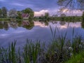 Reflections of St Leonard`s church in Hartley Mauditt Pond, South Downs National Park, UK