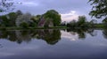 Reflections of St Leonard`s church in Hartley Mauditt Pond, South Downs National Park, UK