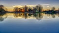 Sunset on Hartley Mauditt pond towards St Leonard`s Church, South Downs National Park, Hampshire, UK