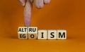 Altruism or egoism symbol. Businessman turns wooden cubes and changes the word `egoism` to `altruism`. Beautiful orange backgr