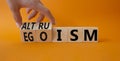 Altruism and Egoism symbol. Hand turns a cube and changes the word Egoism to Altruism. Beautiful orange background. Businessman