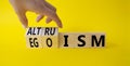 Altruism and Egoism symbol. Hand turns a cube and changes the word Egoism to Altruism. Beautiful yellow background. Businessman