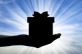 Altruism. Silhouette of a hand giving a gift Royalty Free Stock Photo