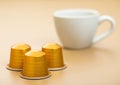 Aluminium coffee capsules pods for coffee machine with white cup on beige background Royalty Free Stock Photo