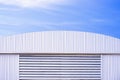 Aluminium louver on corrugated steel wall of warehouse building with curve metal roof against blue sky background