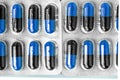 Aluminum blisters with colored black and blue oval capsules neat flat lay