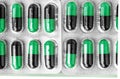 Aluminum blisters with colored black and green oval capsules neat flat lay