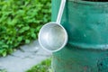 An aluminum bucket hangs on the edge of an iron water tank.